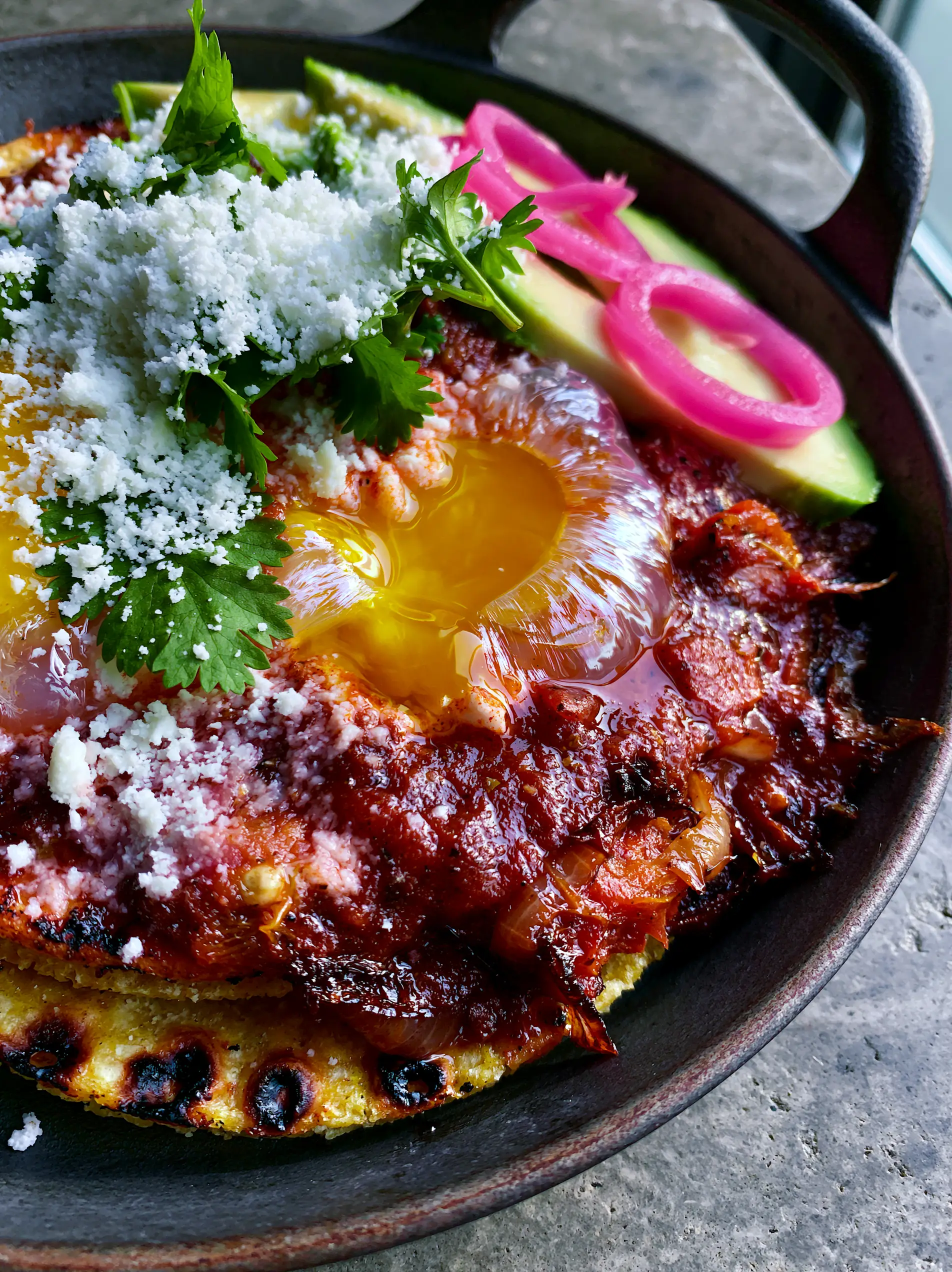 Huevos Rancheros Recipe: Authentic Roasted Salsa and Charred Corn Tortillas 3 Macro shot of sunny-side up eggs on charred tortillas drenched in chunky crimson ranchero sauce. (huevos rancheros)