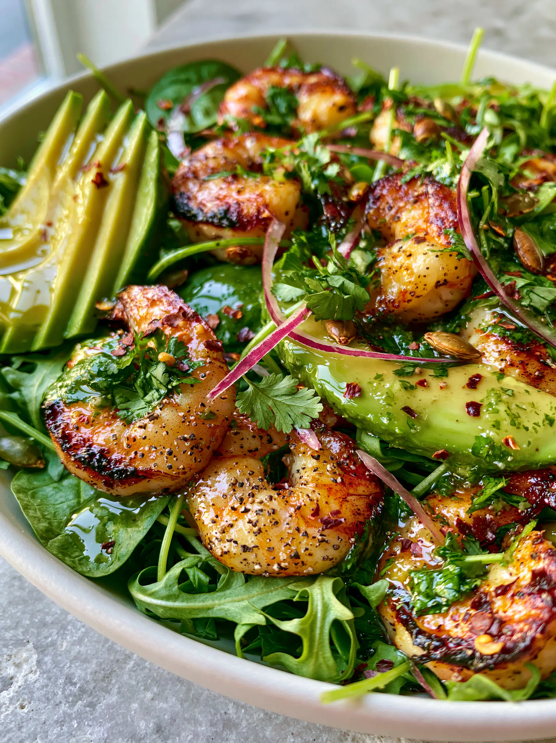 Shrimp Avocado Salad with Cilantro Lime Vinaigrette and Charred Pepitas 3 Macro eye-level shot of seared jumbo shrimp with charred edges and buttery avocado wedges. (shrimp avocado salad)