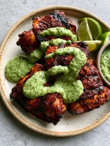 High-angle shot of charred Peruvian Grilled Chicken on a rustic plate. (Peruvian Grilled Chicken)