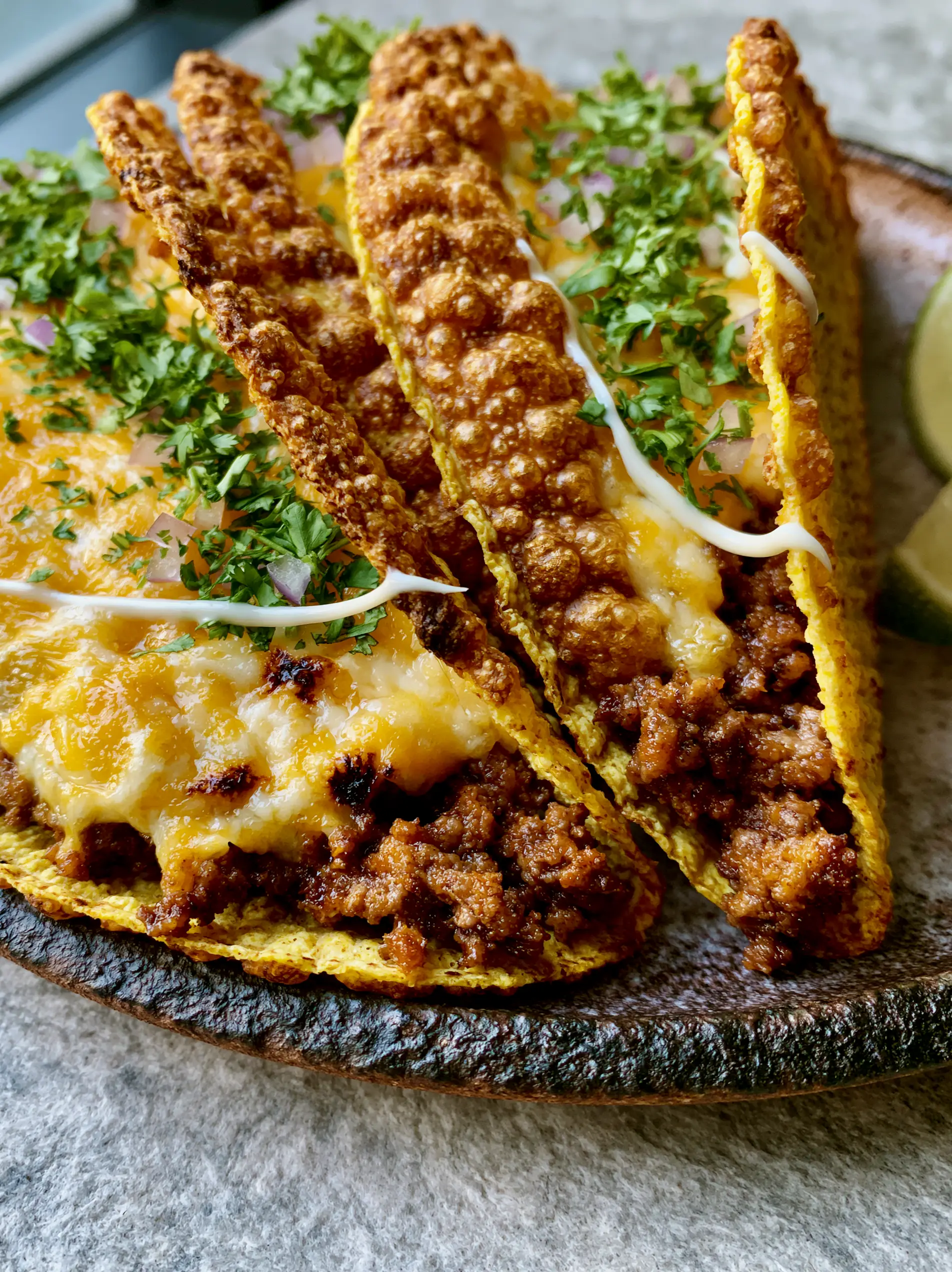 Extreme close-up of blistered golden corn tortillas filled with juicy beef and melted cheddar. (air fryer tacos)