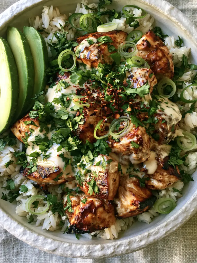 Coconut Chicken Rice Bowls with Creamy Ivory Sauce 1 A detailed overhead shot of the thick ivory coconut sauce drizzled over seared chicken in a Coconut Chicken Rice Bowl.