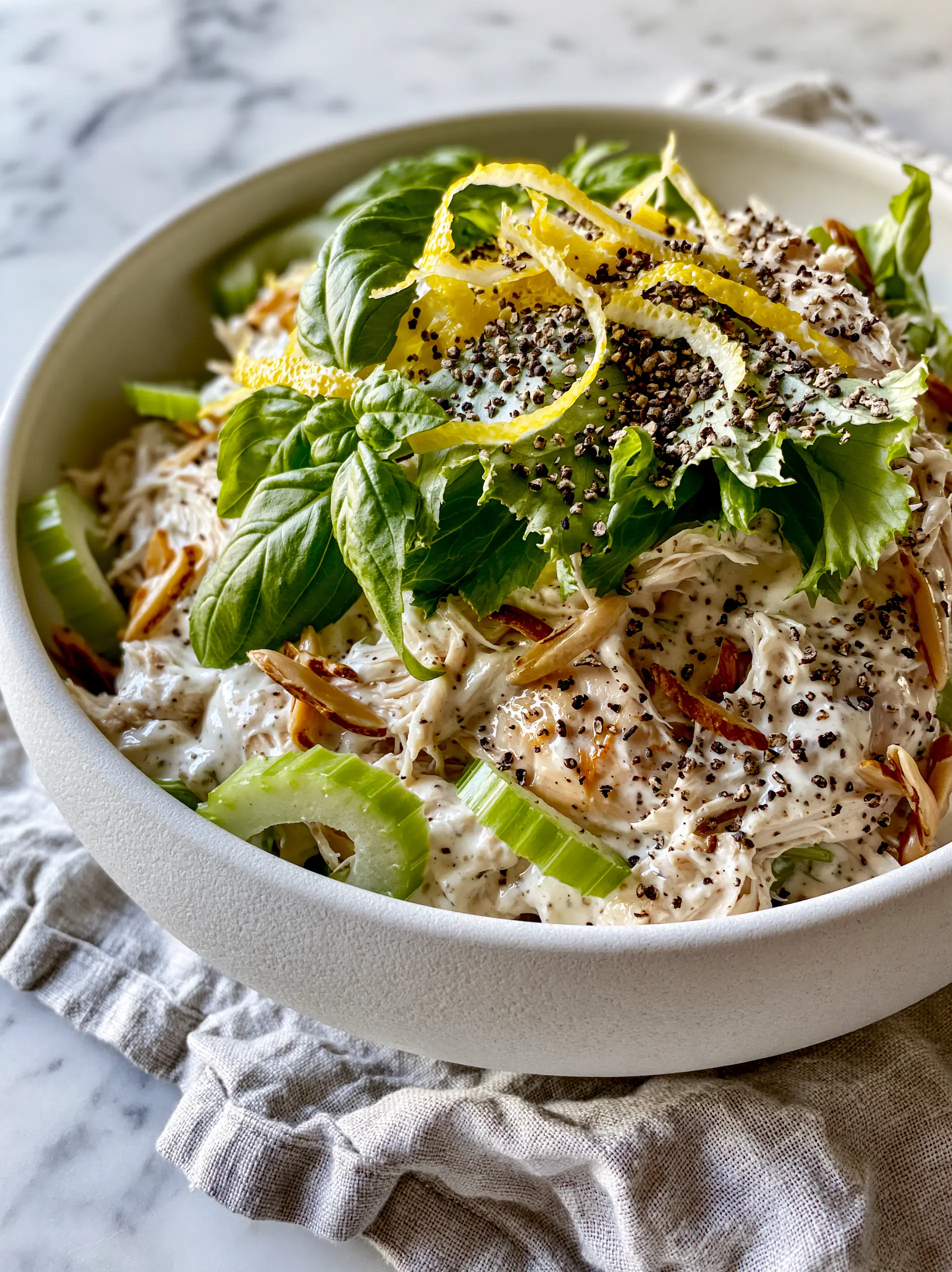 Lemon Basil Chicken Salad with Creamy Greek Yogurt Dressing 3 Lemon Basil Chicken Salad served in a matte white ceramic bowl on a grey linen napkin with morning window light.