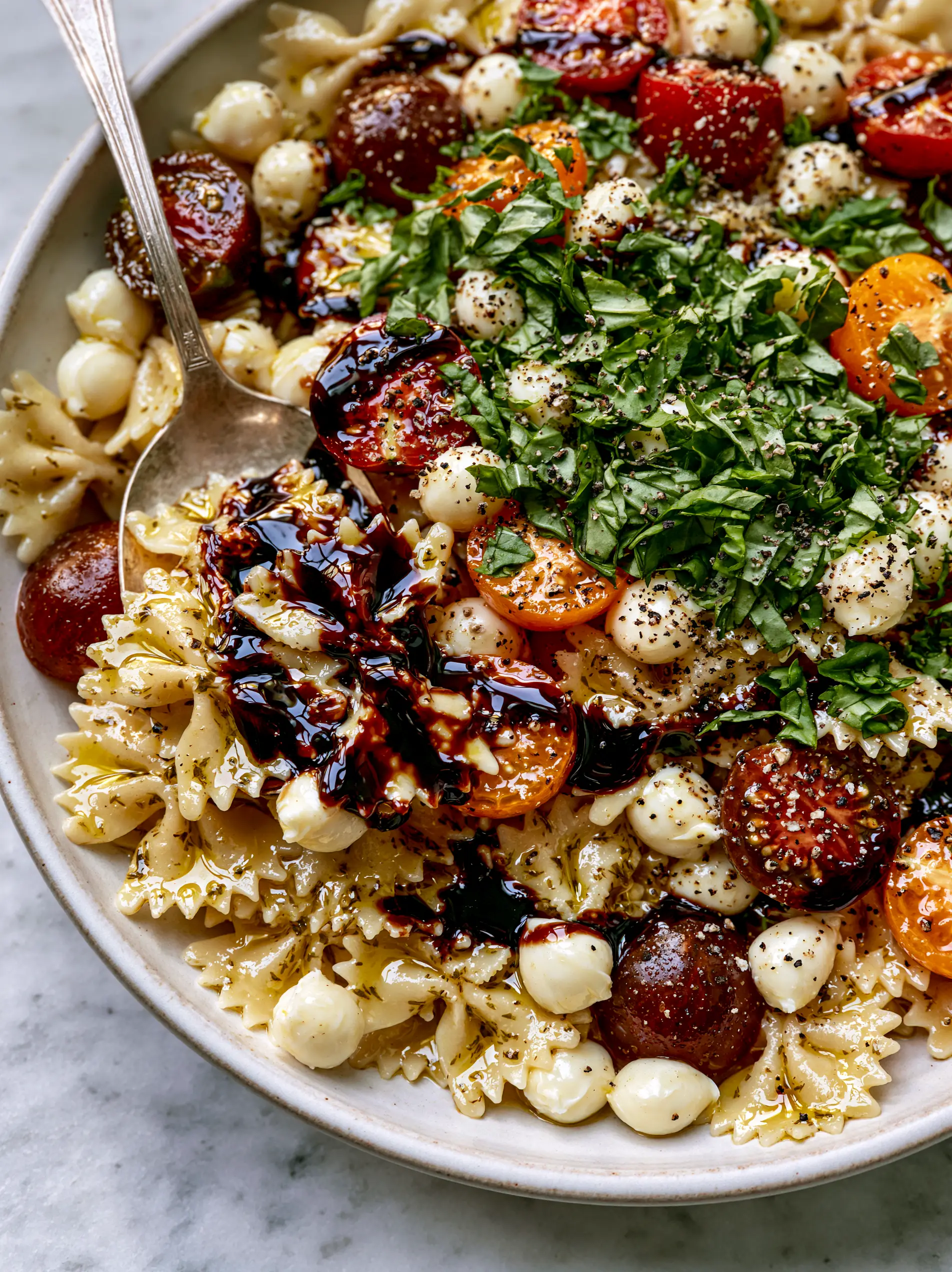 Caprese Pasta Salad Recipe: The Ultimate Balsamic-Drizzled Farfalle 3 Close up shot of al dente farfalle coated in shimmering olive oil herb dressing for a Caprese pasta salad recipe. (Caprese pasta salad recipe)