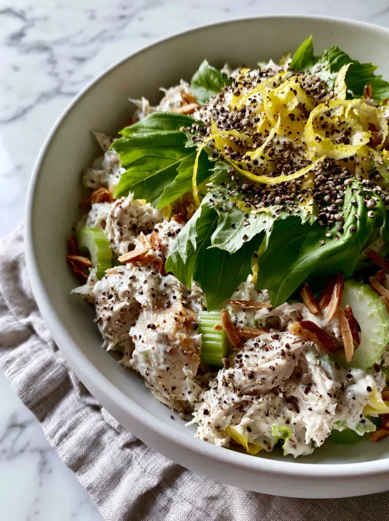 Lemon Basil Chicken Salad with Creamy Greek Yogurt Dressing 1 Detail view of Lemon Basil Chicken Salad showing torn basil leaves and bright yellow lemon zest ribbons.