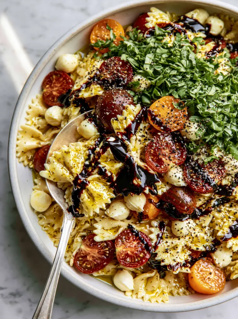 Caprese Pasta Salad Recipe: The Ultimate Balsamic-Drizzled Farfalle 1 Top-down view of heirloom cherry tomatoes and mozzarella pearls in a pasta salad bowl.