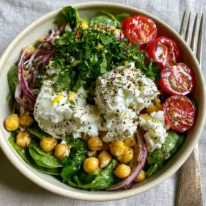 Extreme close-up of glossy chickpeas and halved cherry tomatoes in a chickpea spinach feta salad.