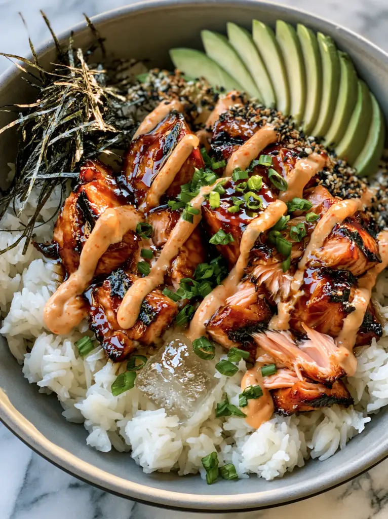 Salmon Rice Bowls with Honey-Soy Glaze and Creamy Spicy Mayo 2 A high-angle photo of a salmon rice bowl in a grey bowl with charred salmon, nori, and a melting ice cube.