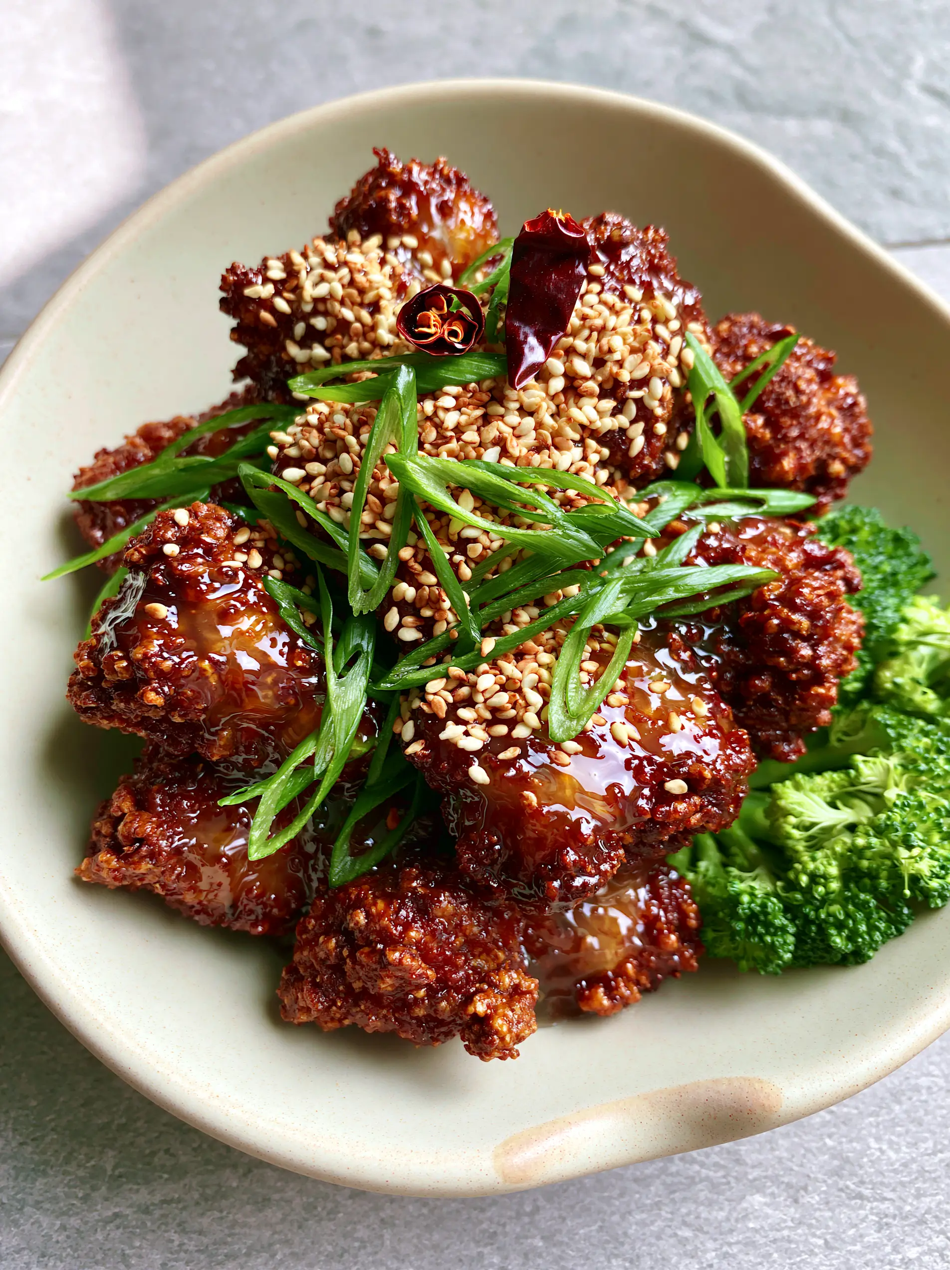 Top-down view of General Tso's Chicken in a matte-cream bowl on a grey stone surface. (General Tso's Chicken)