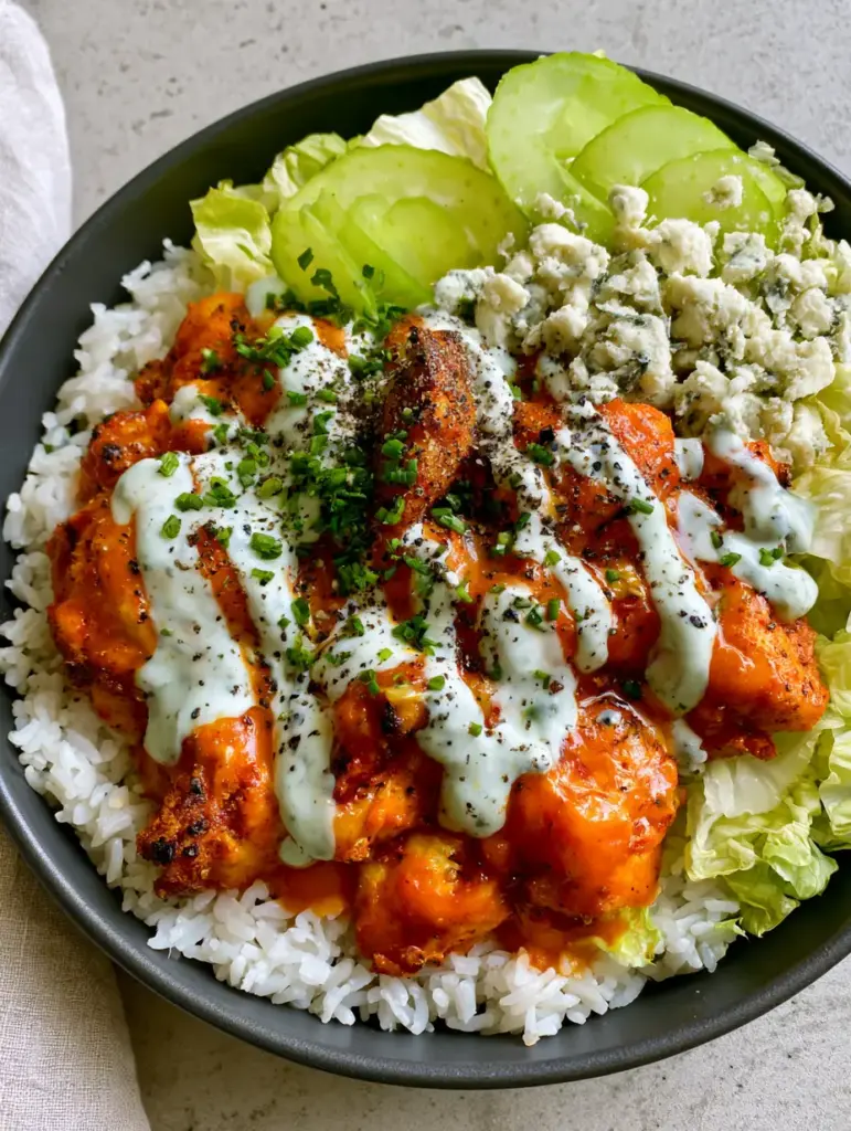 Buffalo Chicken Bowls with Air-Fried Crispy Chicken and Jasmine Rice 1 A matte charcoal bowl filled with buffalo chicken, jasmine rice, and translucent celery slices. (buffalo chicken bowls)