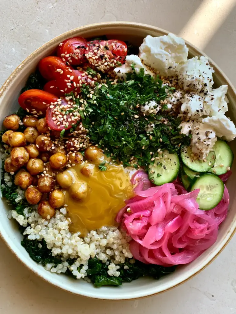 Overhead view of a Mediterranean bowl with thick lemon-tahini dressing pooling in the center.