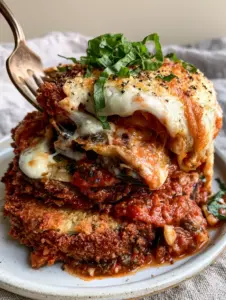 Close-up macro shot of a single stack of panko-crusted eggplant parmesan showing the cheese pull and crispy texture. (eggplant parmesan)