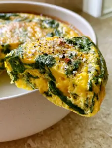 Close up of the souffle-like texture of a Spinach Cottage Cheese Egg Bake with marbled spinach and golden toasted surface.