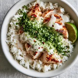 Close up shot of golden-seared chicken breast drizzled with thick coconut lime sauce and lime zest. (Coconut Chicken)